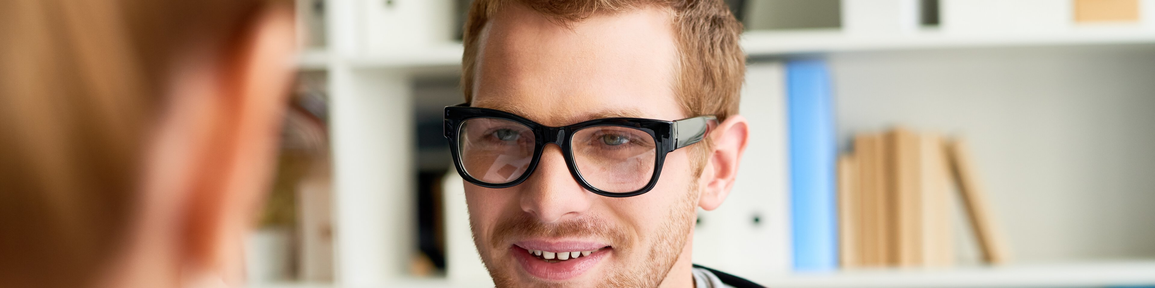Junger Mann mit Brille im Gespräch mit seiner Therapeutin | © mediaphotos - Getty Images/iStockphoto
